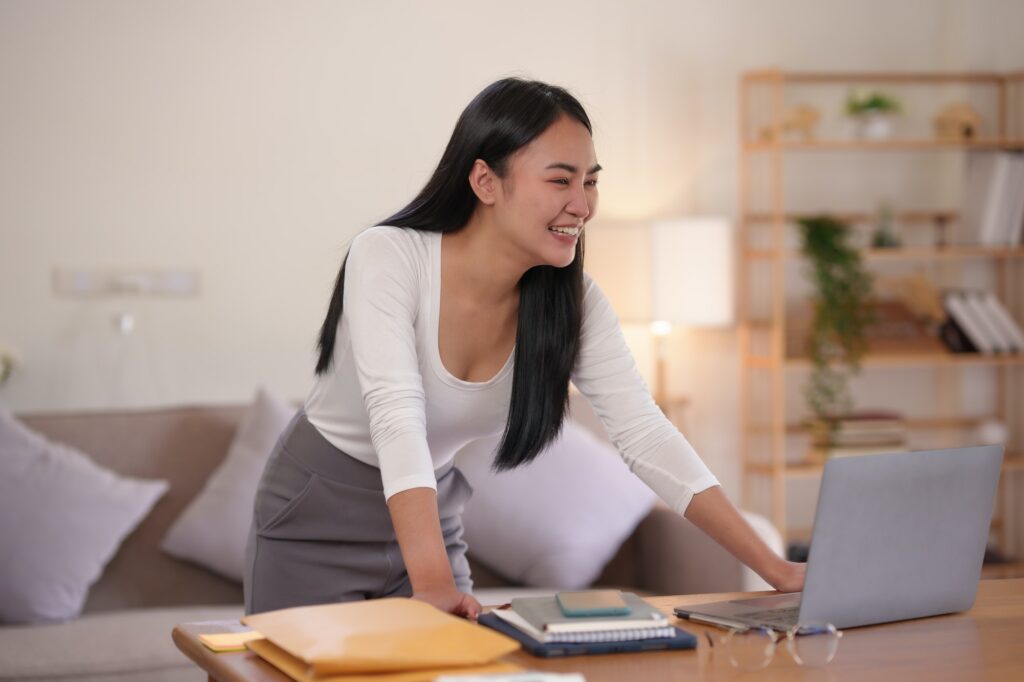 Beautiful young Asian female college students smiling happily using their laptop computer to study